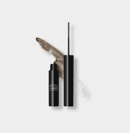 Close-up of Jenn of Arch Browza Brow Ink with a brush applicator showing dark brow tint on skin and brow hairs.