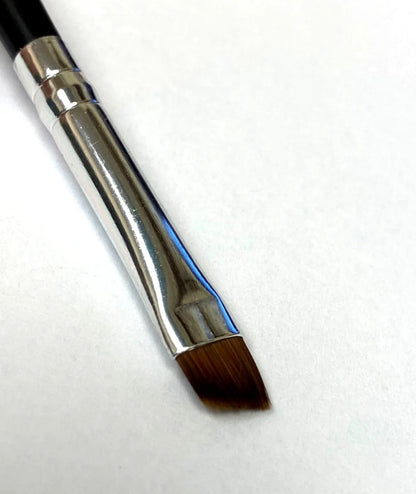 Close up of Jenn of Arch angled liner brush with sleek handle and fine bristles for precise eyeliner application or eyebrow fill